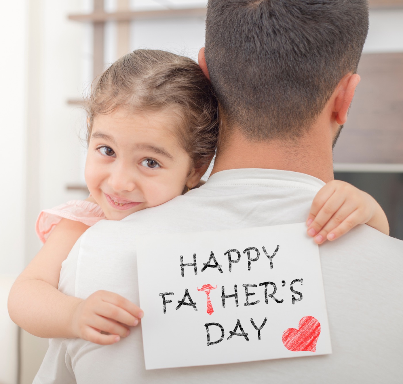 Daughter hugging her dad while holding a Happy Father's Day card